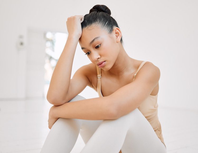 A young ballet dancer resting with her head in her hand